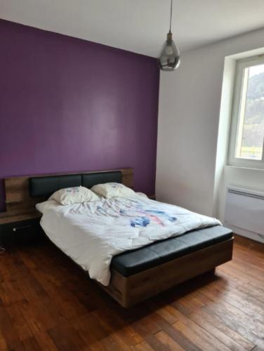 Ce lit se trouve dans une chambre dotée d'un mur violet. dans l'établissement Apt or chalet near the slopes Briançon, à Briançon