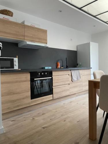 La cuisine est équipée d'armoires en bois et d'un four noir. dans l'établissement La jolie citadine, à Tourcoing