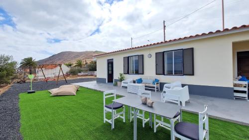 een achtertuin met een tafel, stoelen en gras bij Casa da Ponta by Casas dos Lebre in Porto Santo
