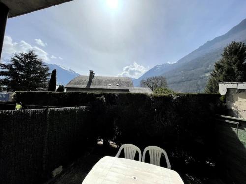 une table et deux chaises blanches sur une terrasse avec des montagnes dans l'établissement l'isard, à Luz-Saint-Sauveur