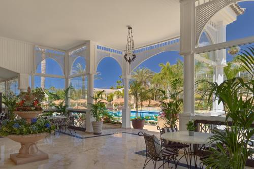 a lobby with tables and chairs and palm trees at Gran Oasis Resort in Playa de las Americas