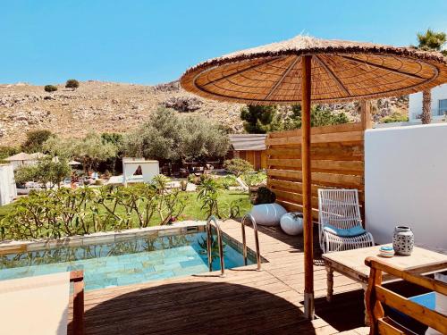 a patio with a table and an umbrella and a pool at Caesars Gardens Hotel & Spa - Adults Only in L&iacute;ndos