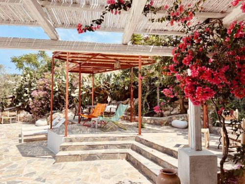 a pergola with flowers and chairs on a patio at Caesars Gardens Hotel & Spa - Adults Only in L&iacute;ndos
