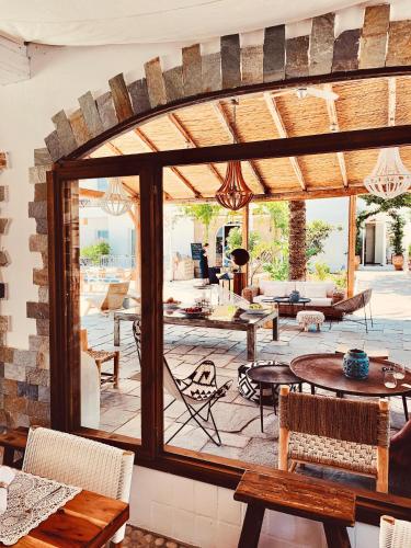 a patio with tables and chairs and a large window at Caesars Gardens Hotel & Spa - Adults Only in Líndos