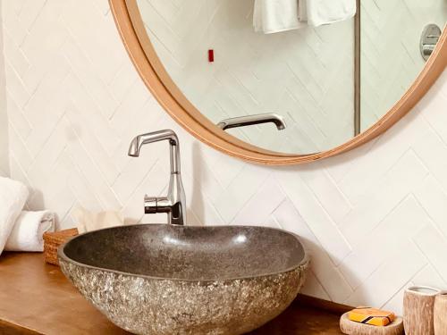 a bathroom with a stone sink and a mirror at Caesars Gardens Hotel & Spa - Adults Only in Líndos