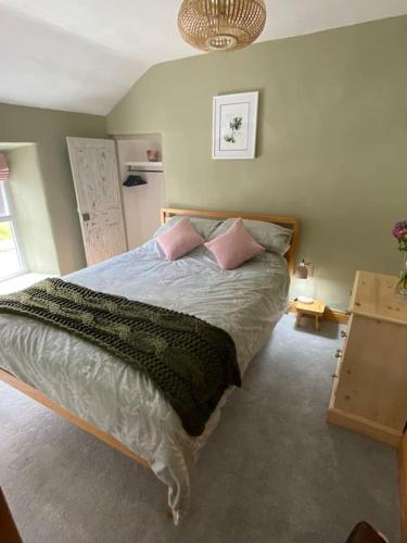 a bedroom with a large bed with pink pillows at Fettlers Cottage, Cumbria in Kirkby Stephen