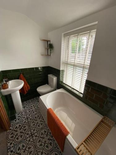 a bathroom with a tub and a toilet and a sink at Fettlers Cottage, Cumbria in Kirkby Stephen