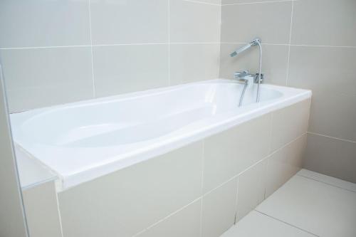 a white bath tub with a faucet in a bathroom at Guest House Auasblick by State House in Windhoek