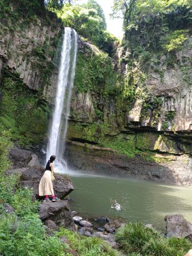 a woman sitting on rocks in front of a waterfall at omusubi guest house (JAPANESE　STYLE） in Mamihara