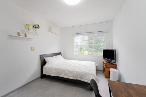 a white bedroom with a bed and a tv at Yang yang Sanjang Love Story in Yangyang
