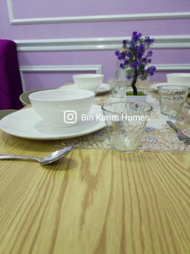 a table with bowls and plates on a wooden table at The Shore KK by Bin Karim Homes in Kota Kinabalu