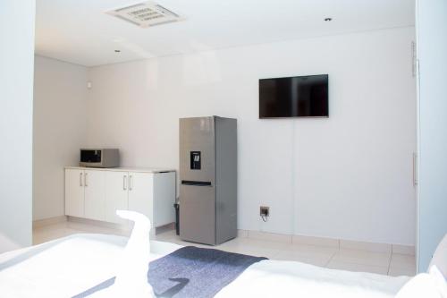 a room with a refrigerator and a tv on the wall at Guest House Auasblick by State House in Windhoek
