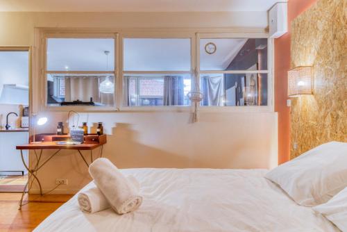 a bedroom with a bed and a table with a window at L'Atelier de l'Artiste - Lumineux - Calme - Wifi in Douai