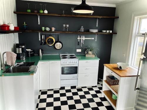 a kitchen with a stove and a checkered floor at Seaside Retreat, Glacier View in Hellissandur