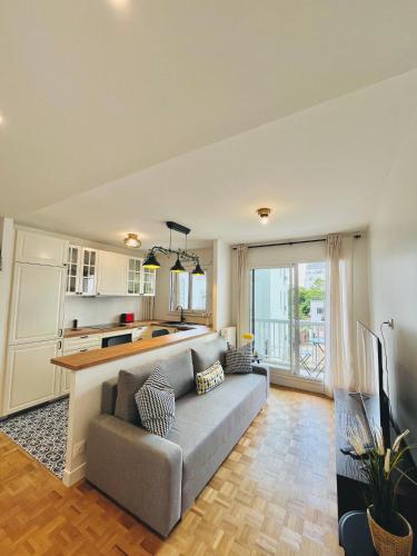 un salon avec un canapé et une cuisine dans l'établissement Défense-2rooms-ForWork-balcony-freeparking, à Courbevoie