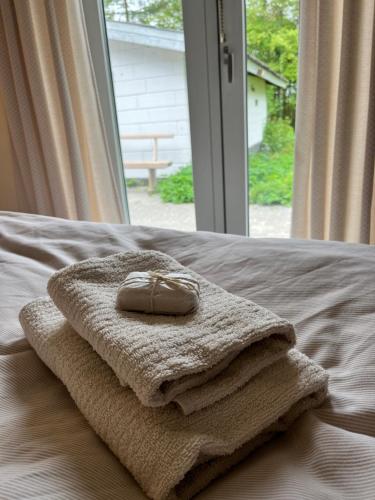 a pile of towels on a bed with a window at Fred og Ro Ferielejlighed in Ulstrup