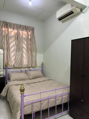 a bedroom with a purple bed and a window at Comfortable Retreat in Megah Ria in Masai