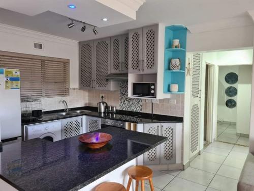a kitchen with a black counter top and blue cabinets at Ramsgate Palms 57 in Ramsgate