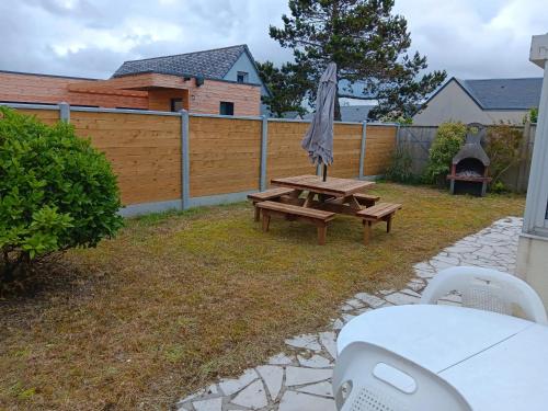 a picnic table with an umbrella in a backyard at Maison charmante à Port-Bail-sur-Mer, grand jardin clos in Port-Bail-sur-Mer