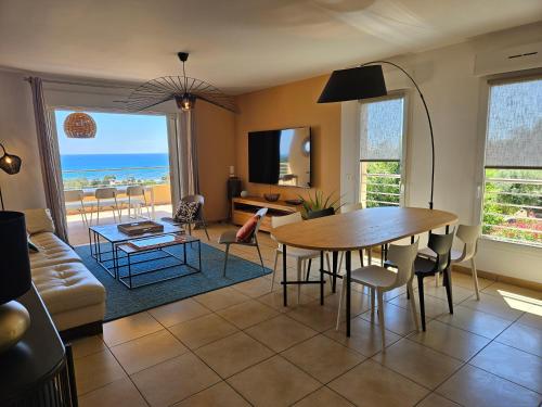 un salon avec une table et des chaises et l'océan dans l'établissement PAOLINA C9 - CLIM - WIFI - VUE MER, à Sari-Solenzara