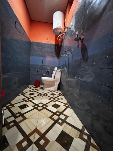 a bathroom with a toilet and a tiled floor at Topal home stay in Gopeshwar