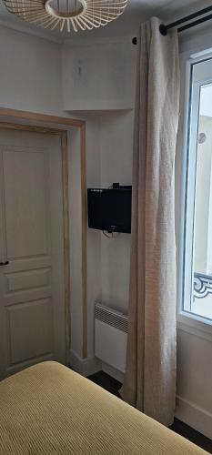une chambre avec un lit, une télévision et une fenêtre dans l'établissement Deux pièces au cœur de Vincennes, à Vincennes