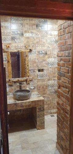 a bathroom with a stone wall with a sink and a mirror at Hotel Riverside Inn in Martuni