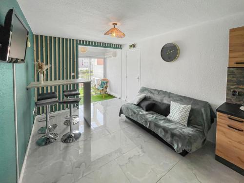 a living room with a couch and a clock on the wall at Évasion Balnéaire au Cap d'Agde in Cap d'Agde