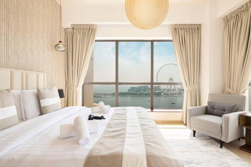 a bedroom with a large bed and a chair and a large window at Dubai Eye & Sea View, 1-min walk to JBR Beach, Luxurious Beach Retreat! in Dubai