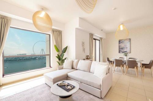 a living room with a white couch and a dining room at Dubai Eye & Sea View, 1-min walk to JBR Beach, Luxurious Beach Retreat! in Dubai