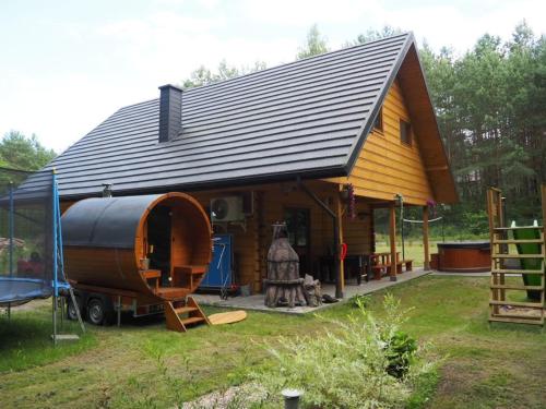 a large wooden house with a large wooden barrel at Bochenówka in Rogowo