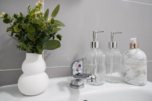 a bathroom sink with two bottles and a vase with flowers at Hububb Luxury Apartment Ealing in Ealing