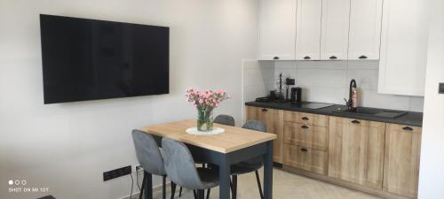 a kitchen with a table with a vase of flowers on it at Apartamenty Szepty Mazur in Odoje