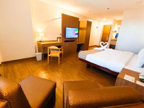 a hotel room with a bed and a tv at Nature's Village Resort in Bacolod