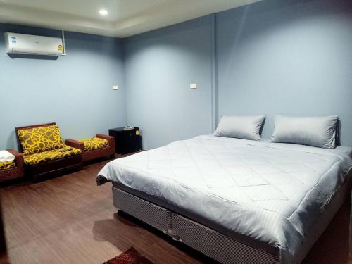a bedroom with a large bed and a chair at เฮือนพรนาคา โฮมสเตย์ in Ban Don Klang
