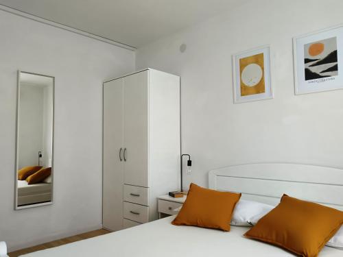 a bedroom with a white cabinet and a bed with orange pillows at Apartments Villa Vanja in Povlja