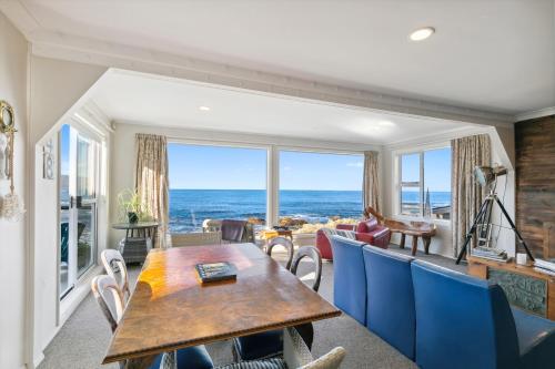 Una sala de estar con una mesa y sillas y el océano. en Pacific Ocean seafront home near airport, en Wellington