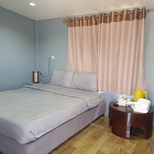a bedroom with a large bed and a table at เฮือนพรนาคา โฮมสเตย์ in Ban Don Klang