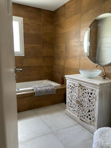 une salle de bain avec une baignoire, un lavabo et un miroir dans l'établissement Villa piscine netflix, à Clarensac