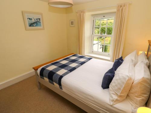 a bedroom with a bed and a window at Orielton Cottage in Dinas