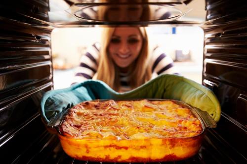 a woman is taking a pizza out of an oven at Toad Hall in Church Stretton