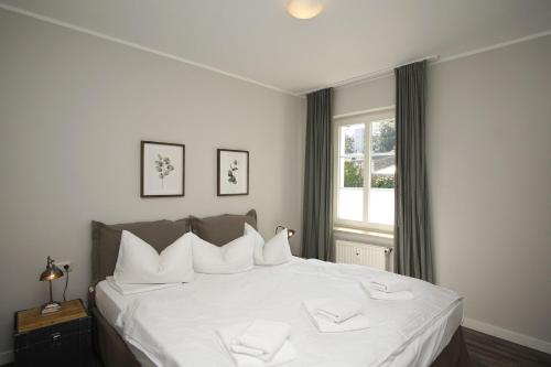 a bedroom with a bed with white sheets and a window at Wintergarten, gratis Nutzung vom AHOI Erlebnisbad in Sellin - Villa Maria FeWo Marlene 34 in Göhren