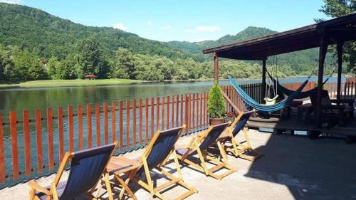 a group of chairs and a hammock on a deck overlooking a river at Vila Vitezov Mir - Drina in Vrhpolje