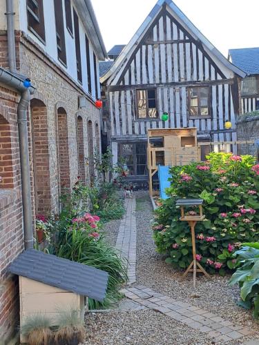 a garden in a building with flowers and a bench at Pont'hôtemer - Appartement, Centre de Pont-Audemer in Pont-Audemer