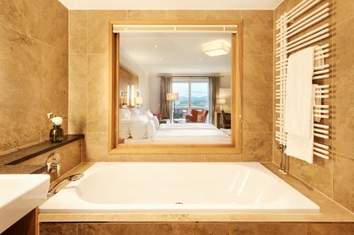 a bath tub in a bathroom with a large mirror at Hotel Auf der Gsteig GmbH in Lechbruck