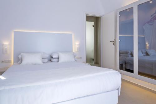 a white bedroom with a large white bed at Art Hotel Santorini in Pirgos