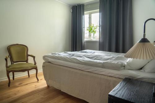 a bedroom with a bed and a chair and a lamp at Kackelstugan in Borgholm