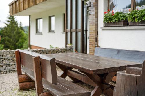 a wooden picnic table and two benches in front of a building at Fuchsmichelhof 4 in Seebach