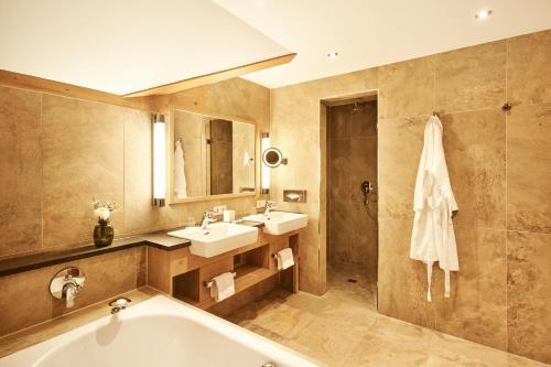 a bathroom with a tub and a sink and a shower at Hotel Auf der Gsteig GmbH in Lechbruck