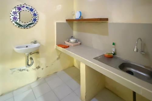 une salle de bain avec un lavabo et un miroir dans l'établissement Raja Asri Guest House Sanur Mitra RedDoorz, à anur